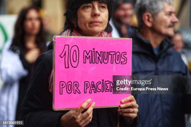 Woman holds a '10 minutes per patient' banner during a demonstration by primary care doctors and pediatricians in the center of Madrid on March 8 in...