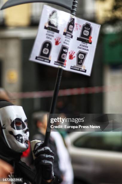 Person wearing a mask holds a banner during a demonstration by primary care doctors and pediatricians in the center of Madrid, March 8 in Madrid,...