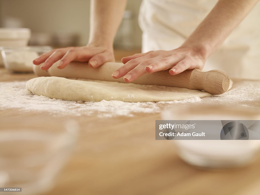 Woman pressing dough with rolling pin