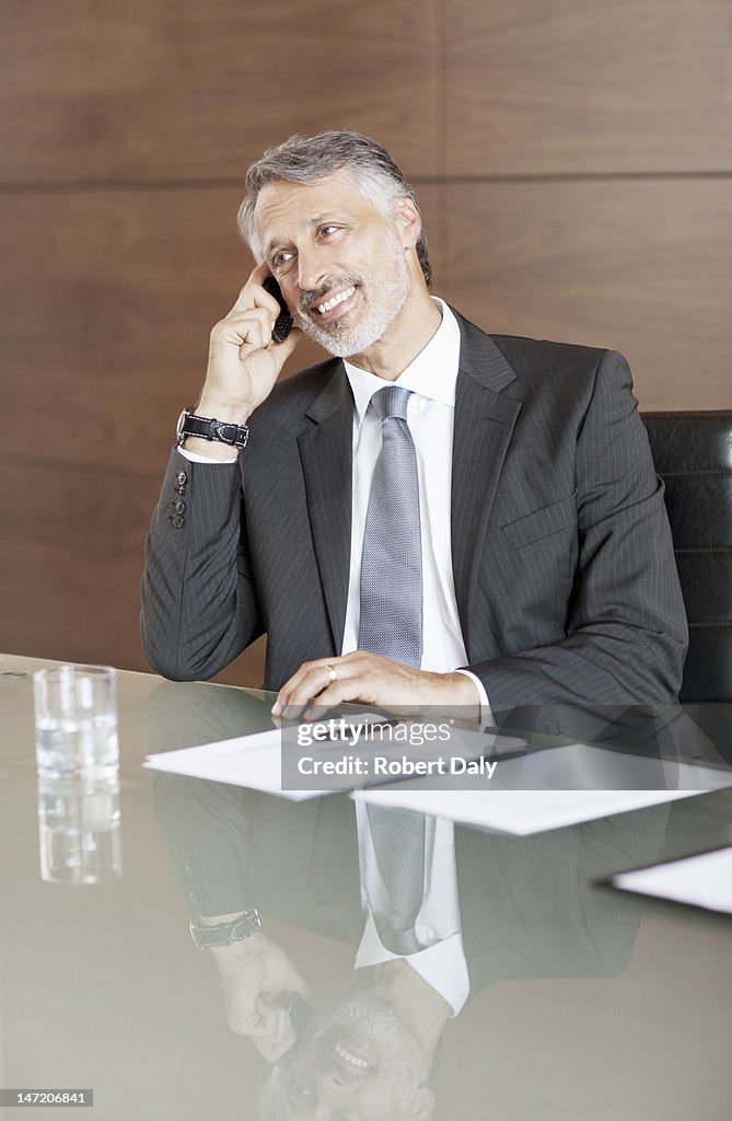 Smiling businessman talking on cell phone in conference room