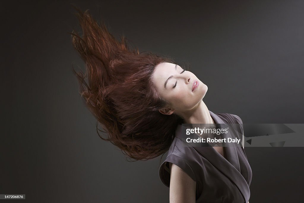 Woman with eyes closed flipping hair