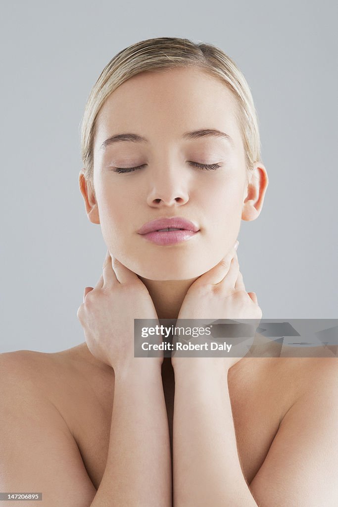 Woman with eyes closed and hands on neck