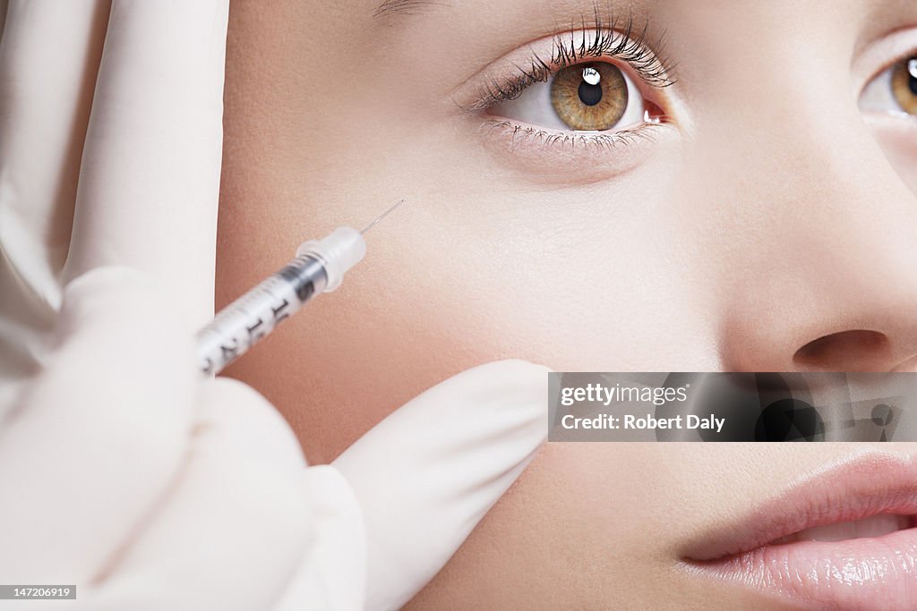 Close up of woman receiving botox injection under eye