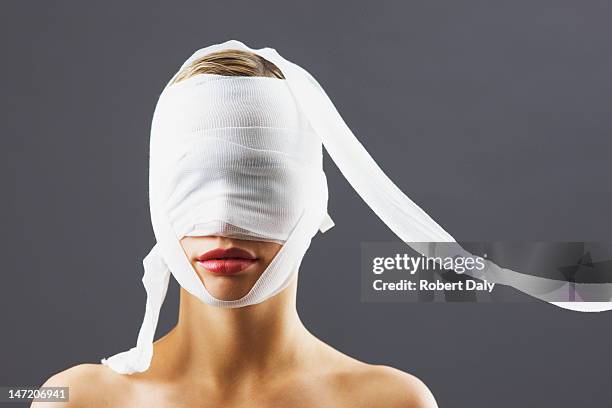 bandage covering woman's face - plastische chirurgie stockfoto's en -beelden