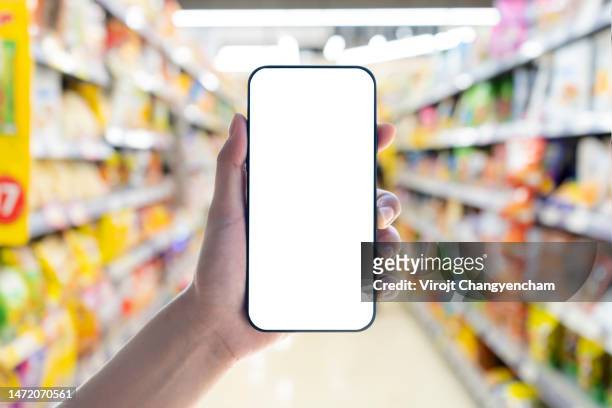 hand holding blank white screen smartphone and supermarket blur background - specimen holder stockfoto's en -beelden