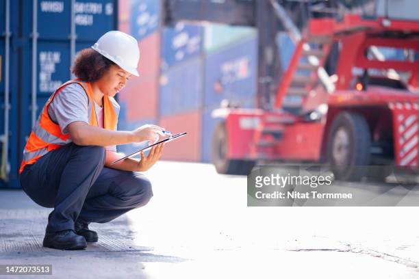 customs clearance process in shipping. african american female customs officer working over a shipping document to verifly and release goods or material imported base on standard method of making customs declarations. - base_(politics) stock-fotos und bilder