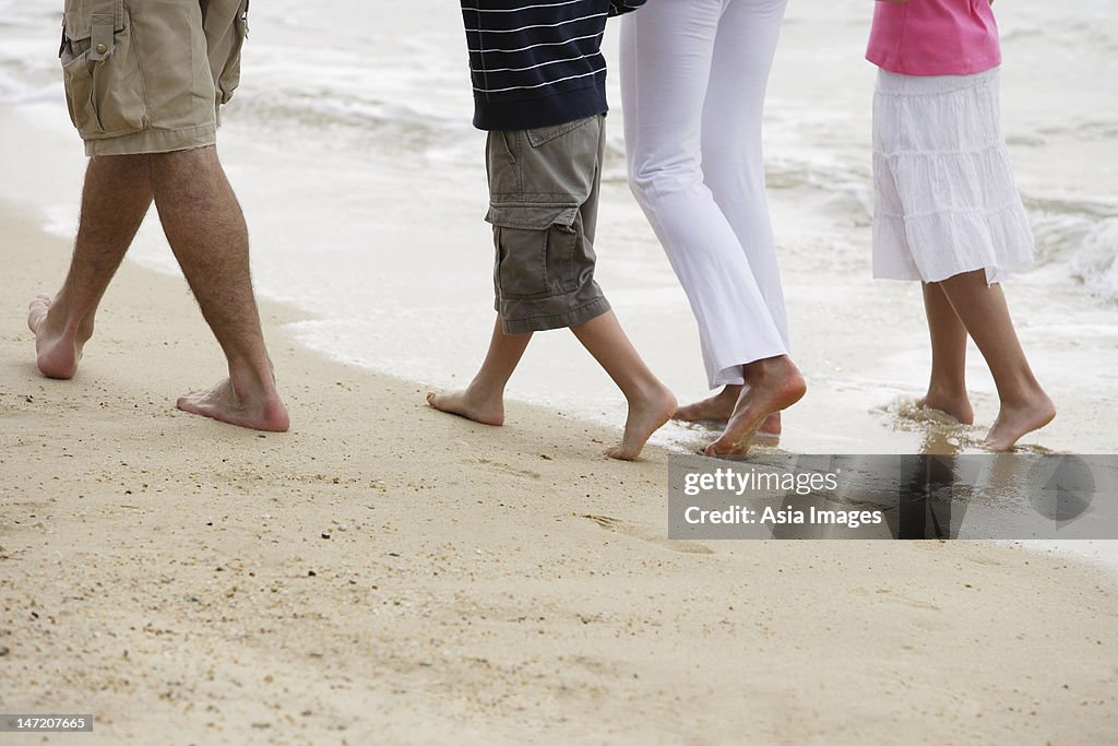 Feet of family walking on beach