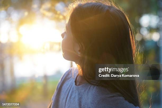 the girl is watching the sunset in the forest. beautiful nature lifestyle and cute girl with lens flare with copy space. - relaxed sunshine happy lens flare bildbanksfoton och bilder