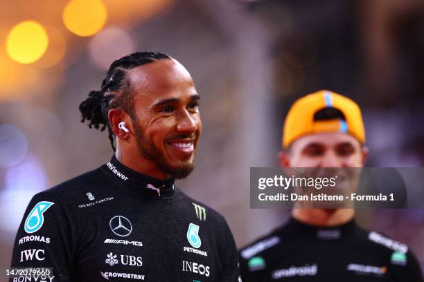 Lewis Hamilton of Great Britain and Mercedes smiles next to Lando Norris of Great Britain and McLaren as he prepares to drive on the grid during the...