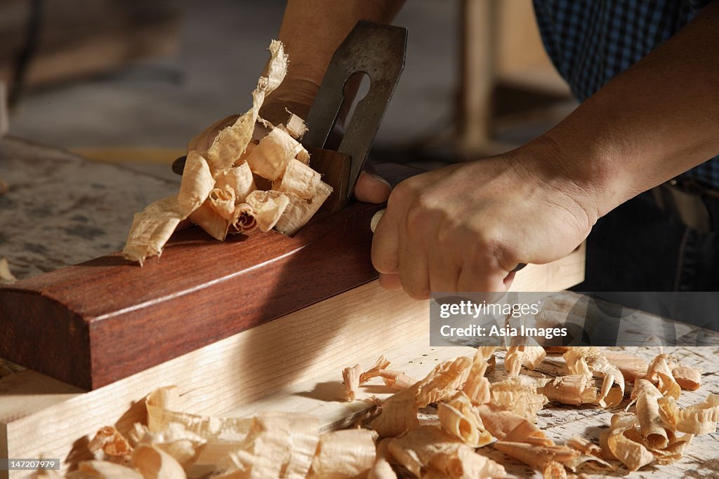 Close up of a carpenter using a block plane.