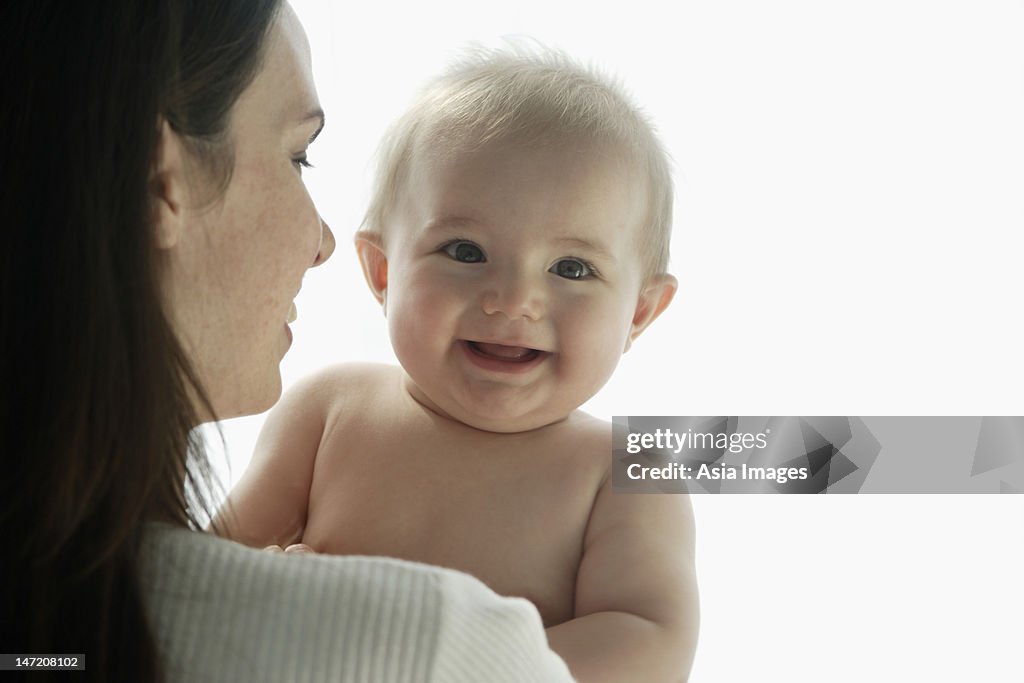 Mother holding baby and smiling.