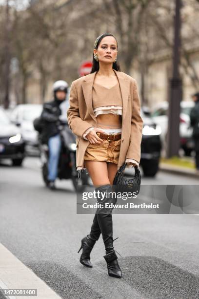 Anna Rosa Vitiello wears silver and gold hair clips, gold large earrings, a beige wool heart-neck / tank-top cropped top from Miu Miu, a beige ripped...