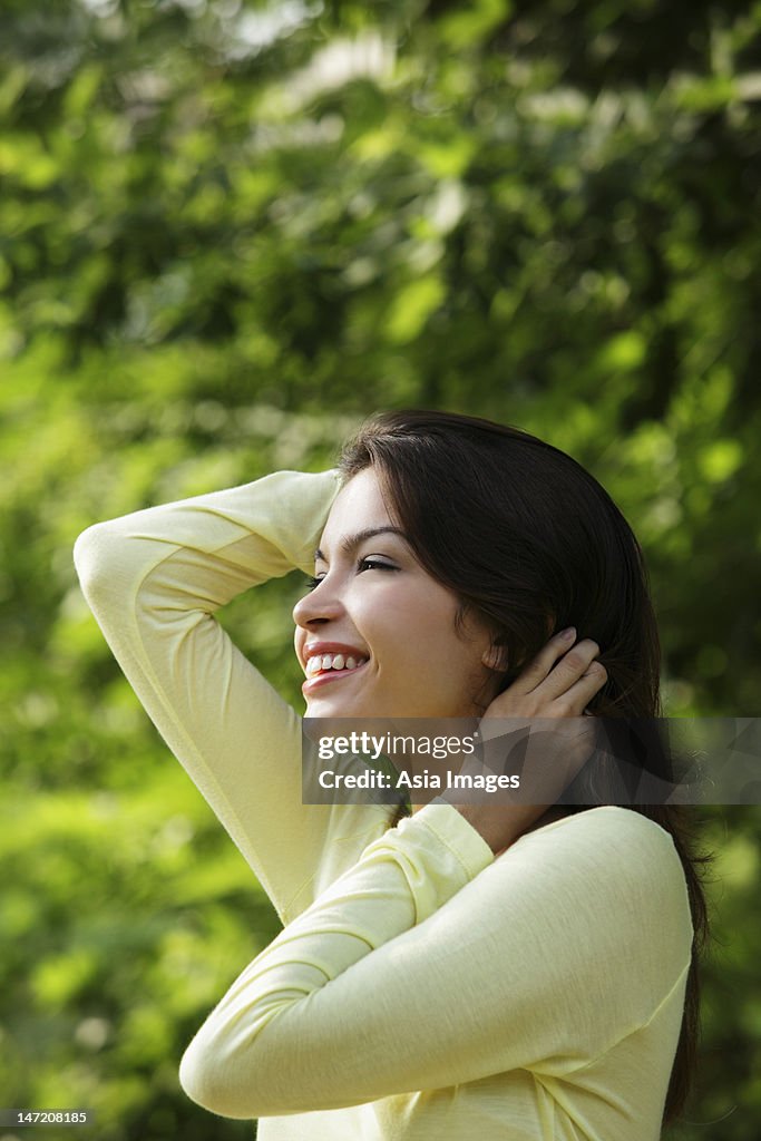 Profile of young woman smiling with hands in hair