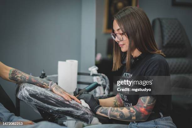 caucasian female tattoo artist, tattooing the female customer in her tattoo studio - tattooing 個照片及圖片檔