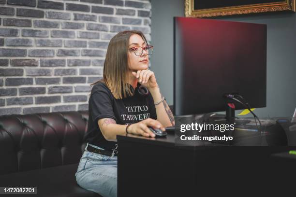 portrait of young tattoo master sitting at computer in tattoo studio choosing tattoo models. - paint microsoft stock pictures, royalty-free photos & images