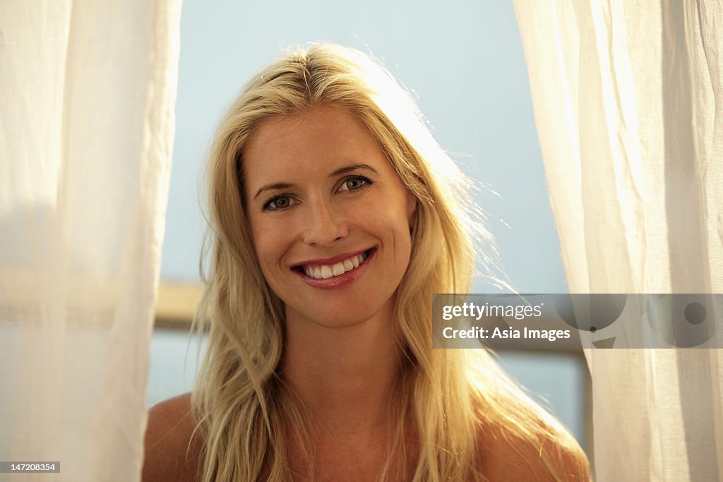 Head shot of blond woman smiling in front of window