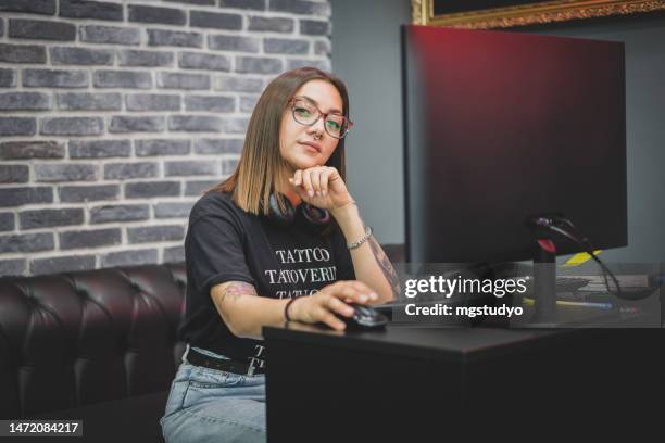 portrait of young tattoo master sitting at computer in tattoo studio choosing tattoo models. - paint microsoft stock pictures, royalty-free photos & images