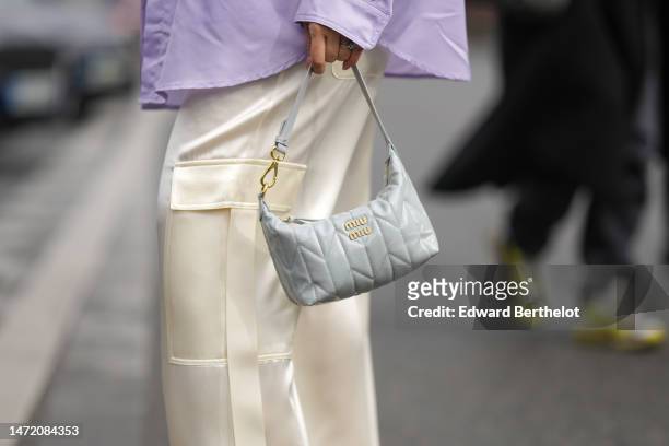 Merve Gorgotz wears a pale purple oversized shirt, pale yellow shiny satin cargo pants, a pale gray shiny varnished leather quilted pattern zipper...