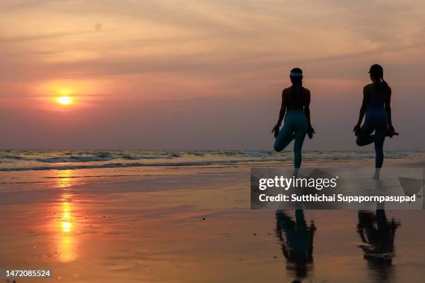 two asian female getting exercise with yoga on the beach during sunset - sunrise yoga stock pictures, royalty-free photos & images