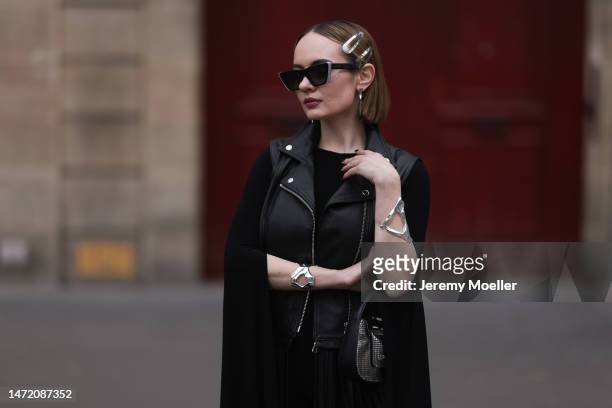 Katya Bychkova seen wearing Louis Vuitton black sunglasses, silver metallic hair clips, AmatoStyle silver jewelry, Norma Kamali black cape jumpsuit,...