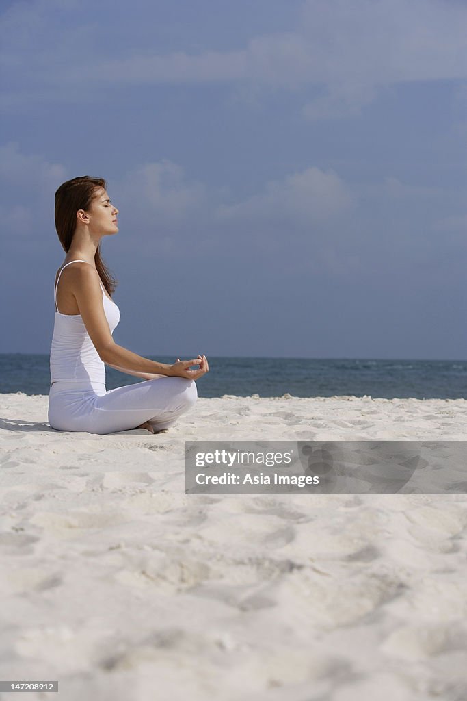 Woman doing yoga on the beach