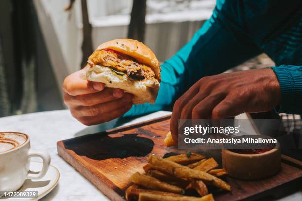 hands hold a vegan burger and dip french fries into the sauce - vegetable kebab stock pictures, royalty-free photos & images