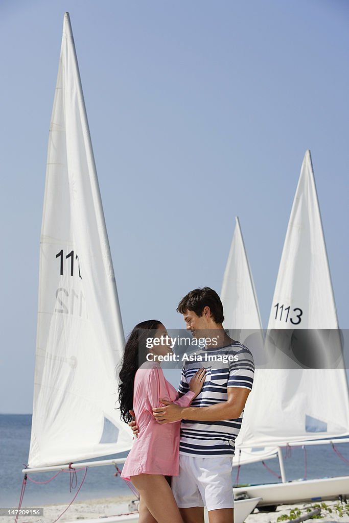 Couple embracing near sailboats