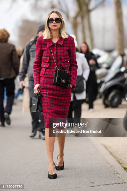 Candela Novembre wears black sunglasses, a dark red and black checkered print pattern tweed jacket from Chanel, a matching dark red and black...