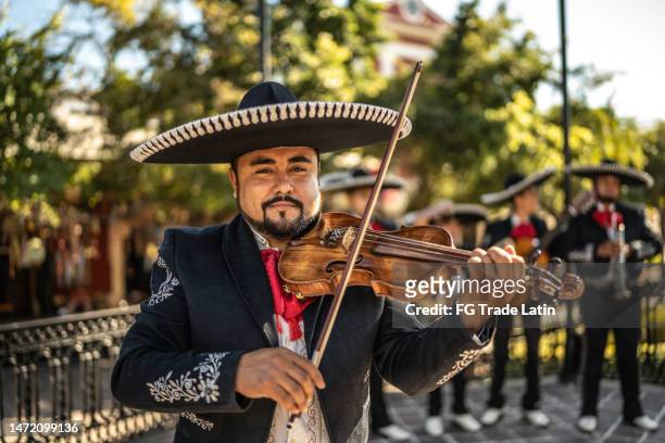 portrait of mid adult man mariachi violinist playing the violin at the historic district - mexican cowboy stock pictures, royalty-free photos & images