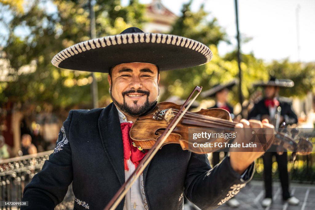 Retrato del violinista mariachi adulto tocando el violín en el distrito histórico