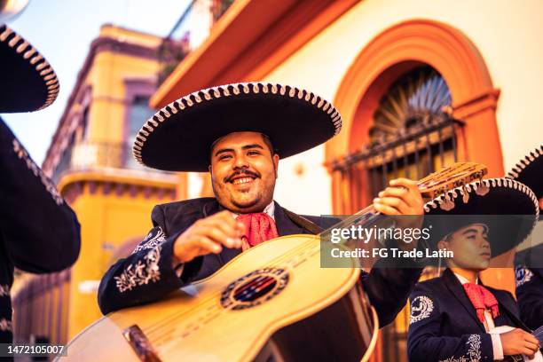 junger mann traditioneller mariachi-gitarrist, der im freien spielt - cinco de mayo stock-fotos und bilder