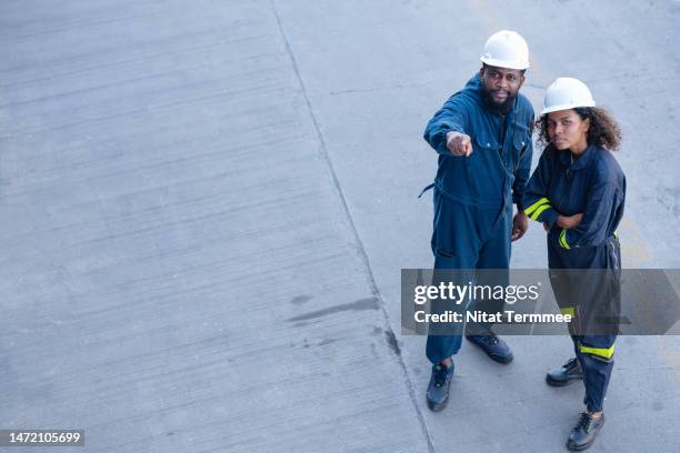 working with an experienced freight forwarder to support your business growth. high-angle view of a male logistics engineer having a discussion with his team to monitor the container loading operations in a shipping yard. - an vorderster front berufsbeschäftigung stock-fotos und bilder