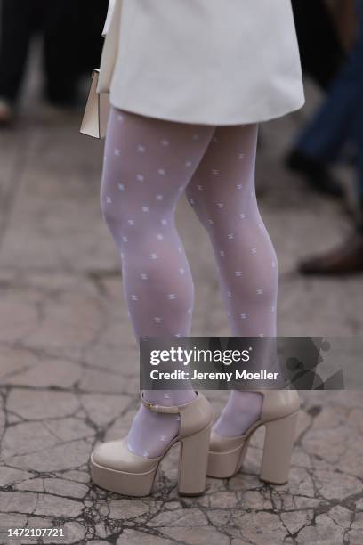 Guest wears Chanel transparent logo tights a white mini dress, Hermes kelly bag and beige plateau high heels, outside Elie Saab show, during Paris...