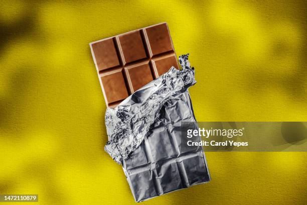bitten chocolate bar in yellow background - uppvecklad bildbanksfoton och bilder