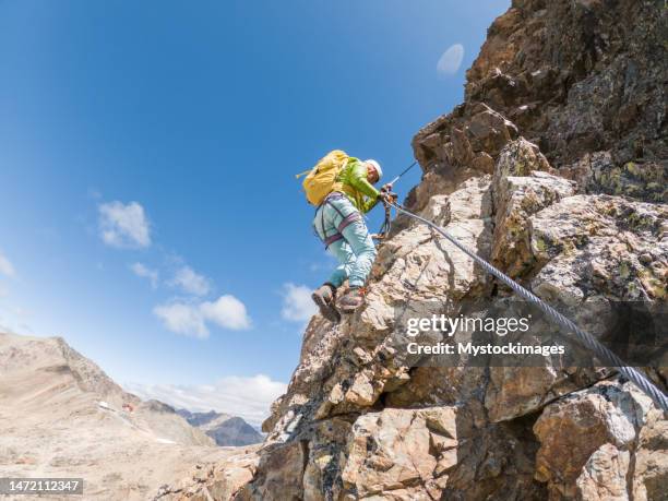 low angle view of woman on via ferrata climbing up, glacier behind - engadin stockfoto's en -beelden