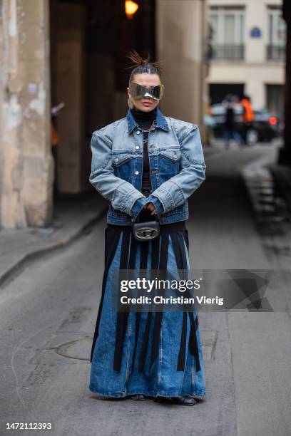 Amelie Stanescu wears two tone denim jacket, flared jeans, black skirt with fringes outside Rokh during Paris Fashion Week - Womenswear Fall Winter...