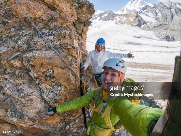 paar auf klettersteig mit selfie, gletscher im hintergrund - wearable kamera stock-fotos und bilder