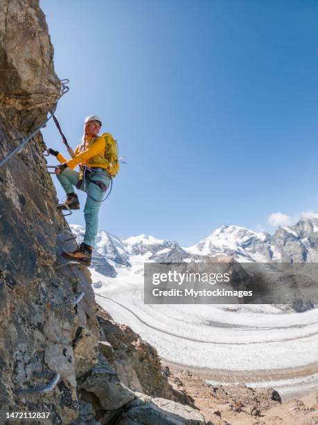 female climber on via ferrata moving up the ladder, success and achievement concept, copy space - clambering stock pictures, royalty-free photos & images