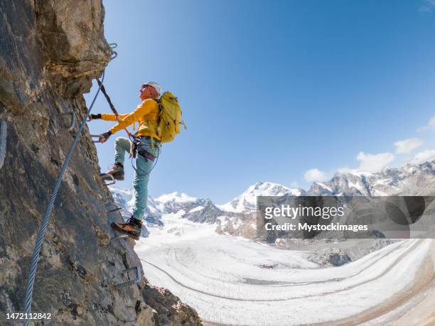 female climber on via ferrata moving up the ladder, success and achievement concept, copy space - clambering stock pictures, royalty-free photos & images