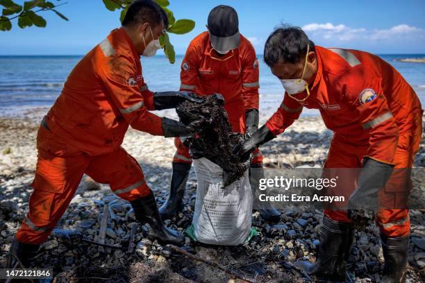 Coast guard personnel clean up an oil slick that has washed ashore from the sunken tanker MT Princess Empress on March 08, 2023 in Pola, Oriental...
