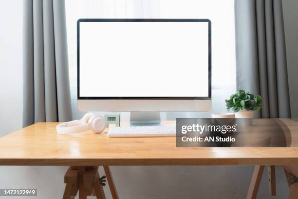 front view of stylish workspace with mock up computer and office supplies gadget. blank screen for graphic display montage. blank screen desktop computer in minimal office room with decorations and copy space. - computers pc stockfoto's en -beelden