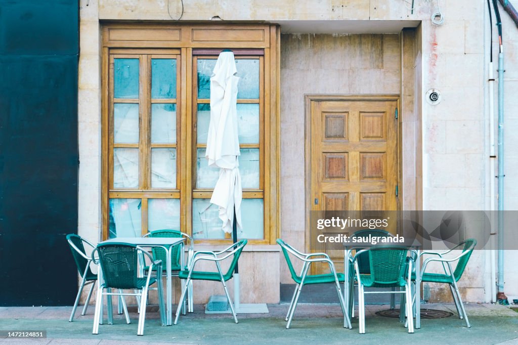 Two cafeteria tables and an umbrella on the street