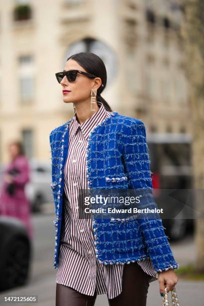 Julia Haghjoo wears black sunglasses, silver earrings, a dark brown and white striped print pattern shirt, a royal blue tweed jacket from Chanel, a...