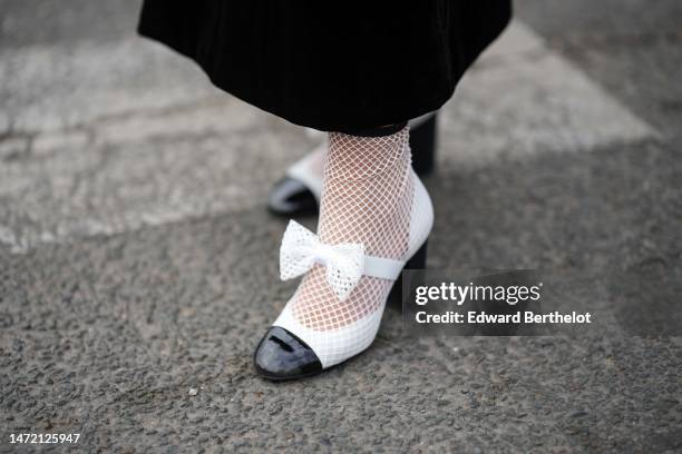 Lala Rudge wears white shiny leather and black toe-cap with embroidered mesh / fishnet socks ankle shoes from Chanel , outside Chanel, during Paris...