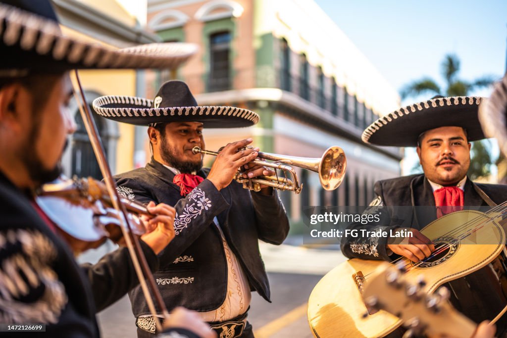 Hombre adulto medio trompetista tradicional de mariachi tocando al aire libre