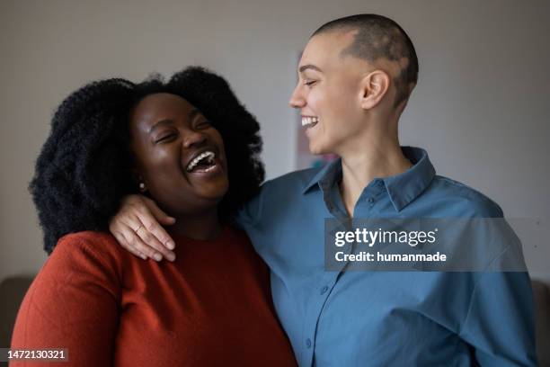 joven lesbiana caucásica mirando a su hermosa pareja afroamericana - alopecia fotografías e imágenes de stock