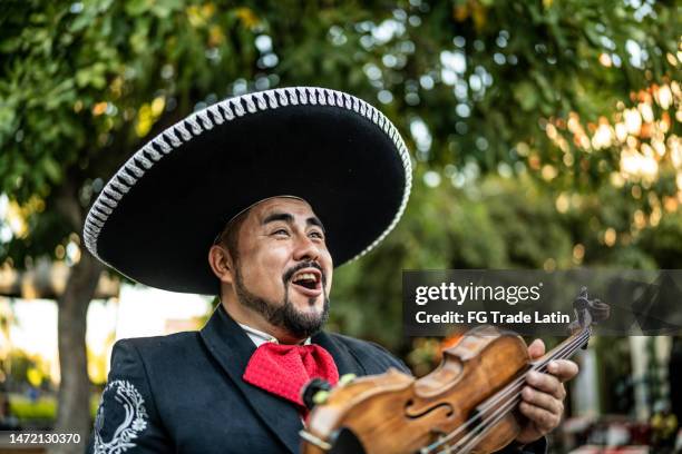 hombre adulto medio mariachi tradicional violinista al aire libre - mariachi fotografías e imágenes de stock