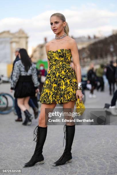 Caroline Daur wears gold and silver diamonds large chain necklaces from Tiffany, a yellow with black print pattern shoulder-off / short dress, a...