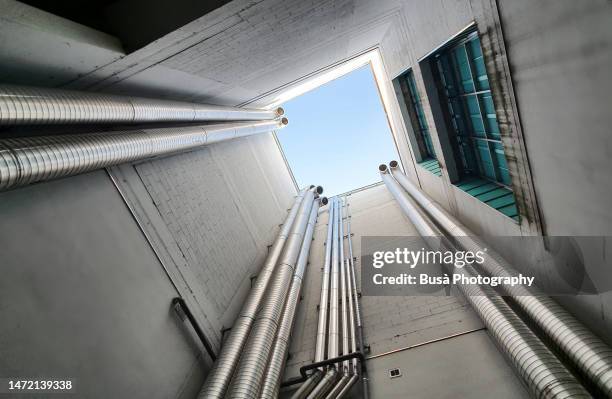 chrome colored air ducts in building shaft - buis laboratoriumapparatuur stockfoto's en -beelden