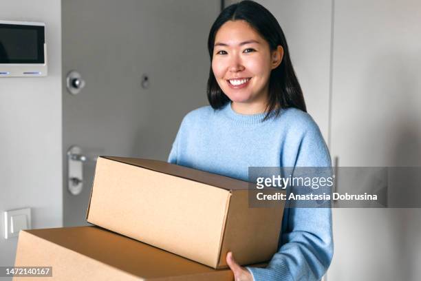 happy woman receiving a package at home - receiving hands stock pictures, royalty-free photos & images